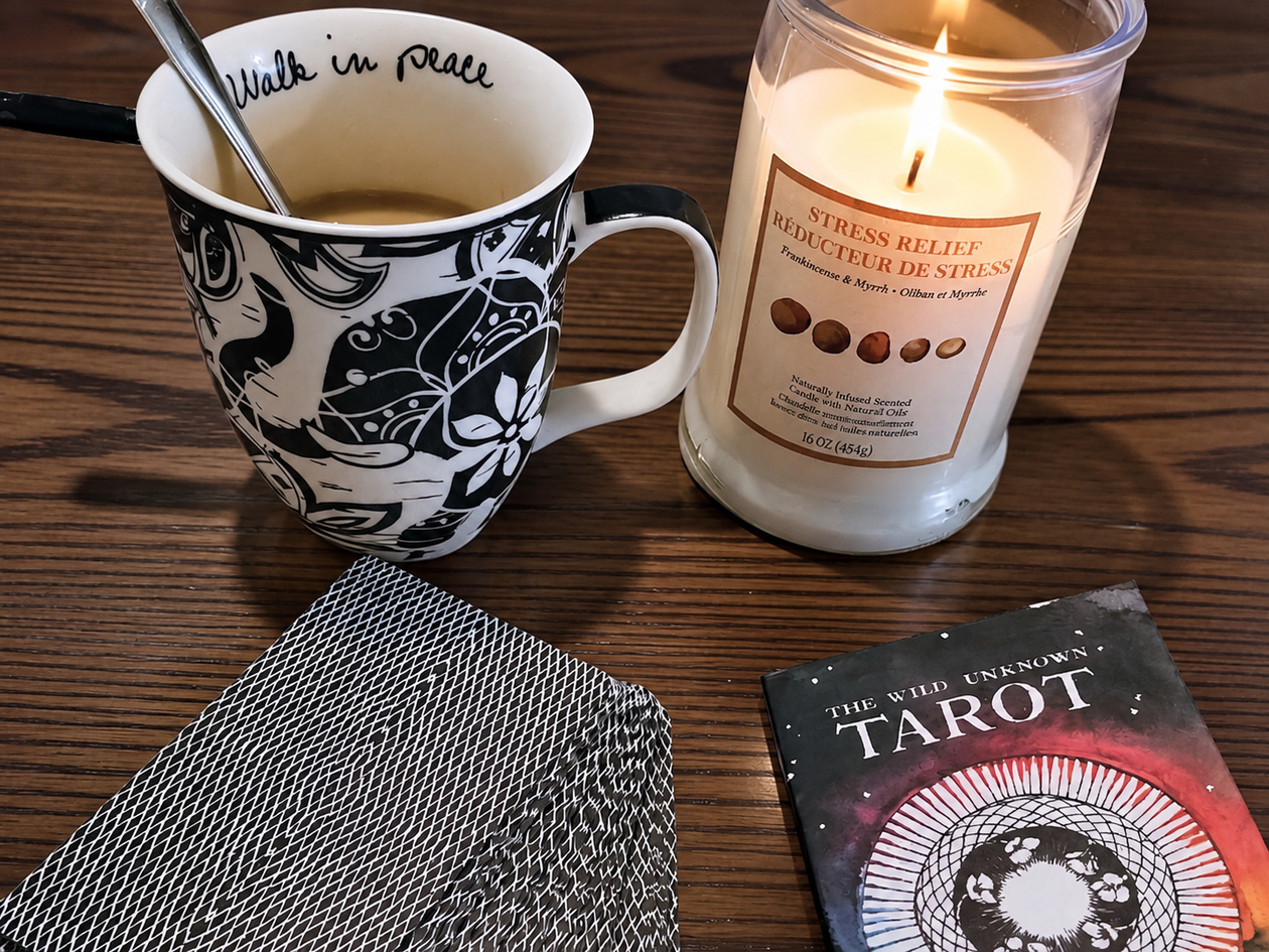 Tarot cards, a lit candle, and a mug of coffee arranged on a tabletop, with the article title overlaid across the center.